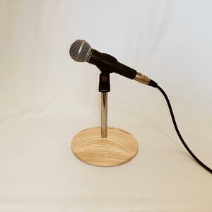 May include: A black microphone on a wooden stand with a silver microphone stand and a black cable.