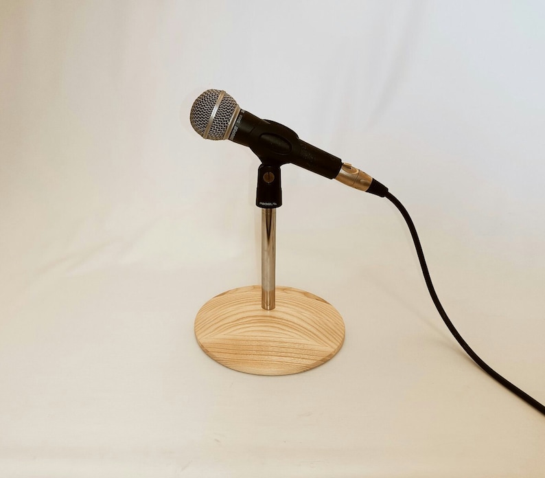 May include: A black microphone on a wooden stand with a silver microphone stand and a black cable.