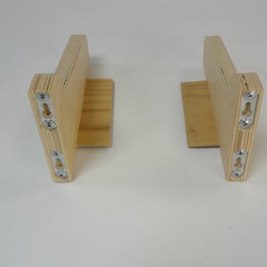 K&ouml;nnte beinhalten: Zwei Holz-Regalbretter mit Metall-Montagehalterungen. Die Halterungen sind aus hellem Holz und haben eine nat&uuml;rliche Oberfl&auml;che.