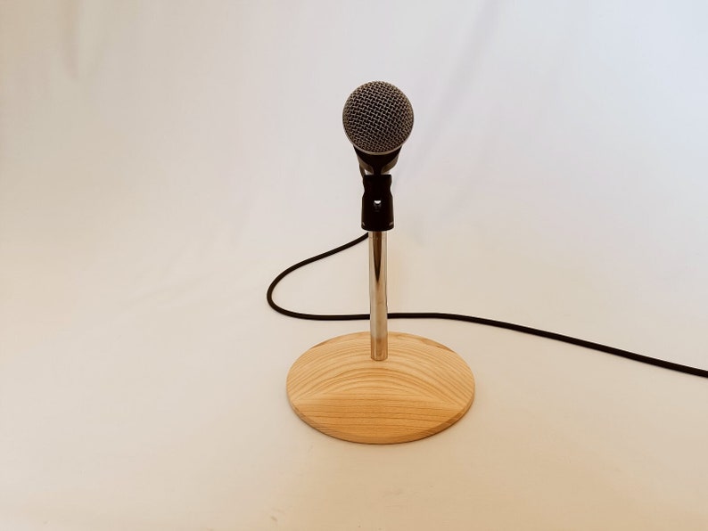 May include: A silver microphone stand with a black microphone and a wooden base.