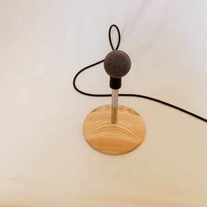 May include: A silver microphone on a wooden stand with a black cable.