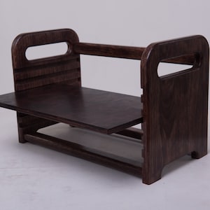 May include: A dark brown wooden shelf unit with two shelves and two open spaces on each side. The shelf unit is made of wood with a dark stain.