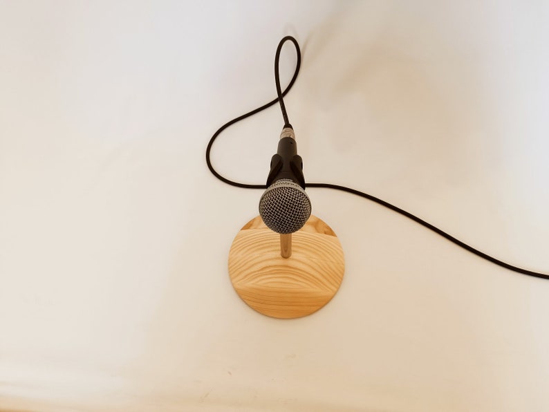 May include: A black microphone on a wooden stand with a black cable.