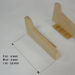 K&ouml;nnte beinhalten: Zwei Laptop-St&auml;nder aus Holz in verschiedenen Gr&ouml;&szlig;en. Die St&auml;nder sind aus Sperrholz und haben eine geschwungene Form. Der Text auf dem Bild lautet: "S size - 4 inches, M size - 8 inches, L size - 12 inches".