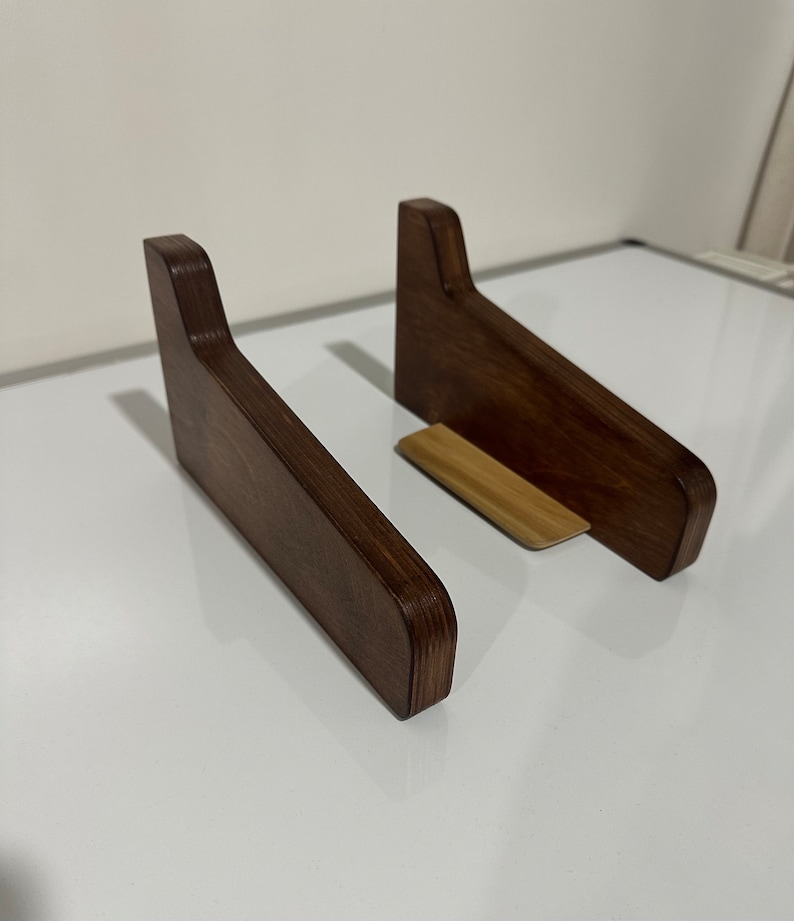 K&ouml;nnte beinhalten: Zwei Laptop-St&auml;nder aus Holz, einer mit einem Akzent aus Naturholz, in einer dunkelbraunen Lasur. Die St&auml;nder sind abgewinkelt, um einen Laptop zu erh&ouml;hen.