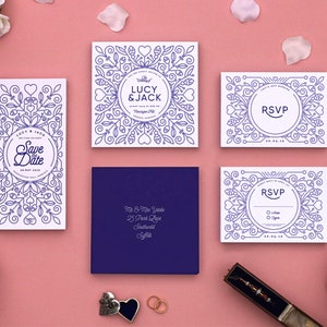 Puede incluir: Un conjunto de invitaciones de boda con un diseño floral blanco y morado. Las invitaciones incluyen una tarjeta de guardar la fecha, una invitación principal, una tarjeta RSVP y una tarjeta de detalles. El texto en las tarjetas dice "Lucy & Jack" y "Save the Date".