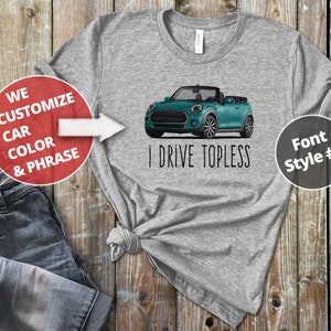 May include: Gray t-shirt with a teal Mini Cooper convertible printed on the front. The text "I Drive Topless" is printed below the car. The text "We Customize Car Color & Phrase" is printed on a red circle in the top left corner. The text "Font Style #2" is printed on a gray circle in the top right corner.