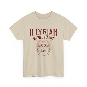 Puede incluir: Una camiseta de color crema con el texto "Illyrian Warrior Camp" en borgoña. Debajo del texto hay un gráfico de un emblema alado con las palabras "Blood Rite Gauntlet" y "Valkyrie Unit", en un estilo vintage.