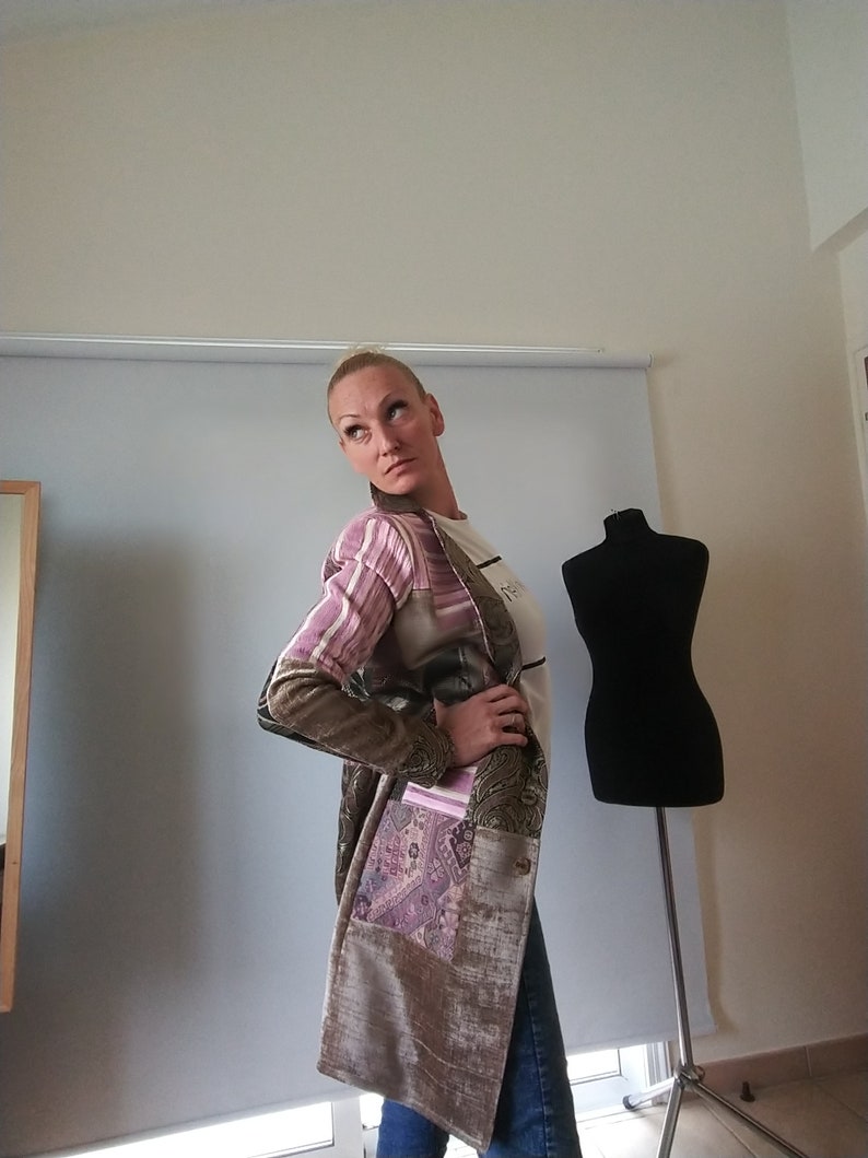K&ouml;nnte beinhalten: Eine Patchwork-Umh&auml;ngetasche mit verschiedenen Stoffen, darunter ein Paisley-Muster und Streifen. Die Tasche hat eine gro&szlig;e Tasche und einen Knopfverschluss. Die Farben umfassen Lila-, Braun- und Goldt&ouml;ne.