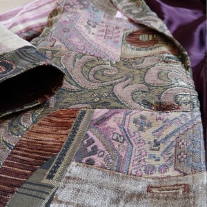 Può includere: Un blazer patchwork con una varietà di tessuti fantasia nei toni del marrone, rosa e oro. La parte inferiore del blazer ha una consistenza vellutata e una fodera in raso viola. Il design include motivi geometrici e floreali.