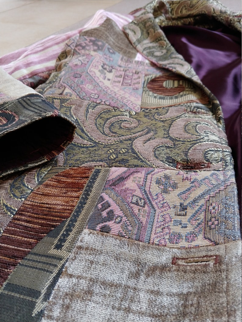 K&ouml;nnte beinhalten: Ein Patchwork-Blazer mit verschiedenen gemusterten Stoffen in Braun-, Rosa- und Goldt&ouml;nen. Der untere Teil des Blazers hat eine samtartige Textur und ein lila Satinfutter. Das Design umfasst geometrische und florale Muster.