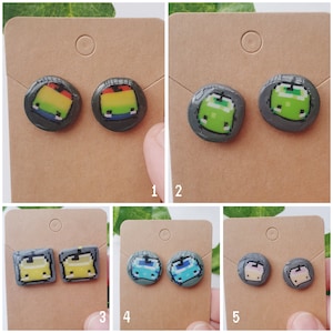 May include: Six pairs of small, round, colorful earrings with pixelated designs. The earrings are displayed on six separate cards with a white background.