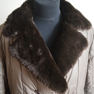 May include: A brown quilted jacket with a large brown faux fur collar. The jacket has a double breasted closure with buttons.