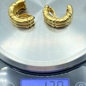 May include: A pair of gold-toned clip-on earrings with a textured, bamboo-like design. The earrings weigh 1.38 ounces.