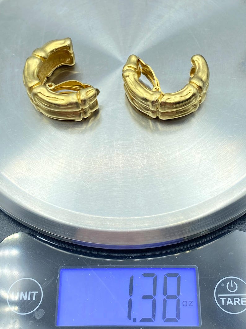 May include: A pair of gold-toned clip-on earrings with a textured, bamboo-like design. The earrings weigh 1.38 ounces.