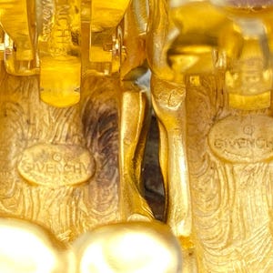 May include: A pair of gold-tone clip-on earrings with a textured design and the word "Givenchy" engraved on the back.