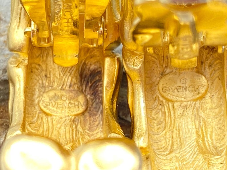 May include: A pair of gold-tone clip-on earrings with a textured design and the word "Givenchy" engraved on the back.