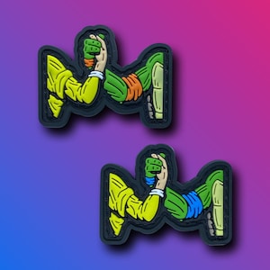 May include: Two black and white arm wrestling patches with yellow and green details. The patches feature two figures arm wrestling, one in yellow and one in green.