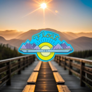 Könnte beinhalten: Ein blauer und gelber Aufkleber mit dem Wort "Float" in einer stilisierten Schrift. Der Aufkleber zeigt eine stilisierte Sonne mit Bergen auf beiden Seiten. Der Aufkleber befindet sich auf einer Holzbrücke mit einem verschwommenen Hintergrund eines Sonnenuntergangs über Bergen.