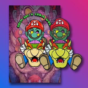 Puede incluir: Dos parches bordados con personajes de dibujos animados verdes y rojos con cabezas en forma de hongo. Los personajes llevan sombreros rojos y azules y montan criaturas amarillas y marrones. El texto "GRIM EDC x CROM WOW" es visible en el fondo.