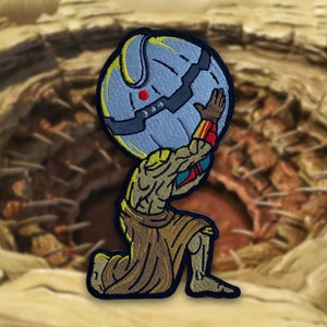 May include: An embroidered patch depicting a muscular figure kneeling and holding a large, round, blue and yellow object. The figure is wearing a brown tunic and has a red and yellow design on its arm.