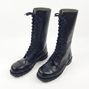 Könnte beinhalten: Paar schwarze Leder-Kampfstiefel mit Schnürdesign. Die Stiefel haben eine runde Spitze und einen hohen Schaft, passend für verschiedene Stile. Die Stiefel sind aus glattem, strapazierfähigem Leder.