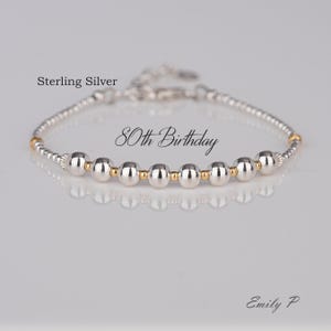 May include: Sterling silver bracelet with gold beads and the text "80th Birthday".