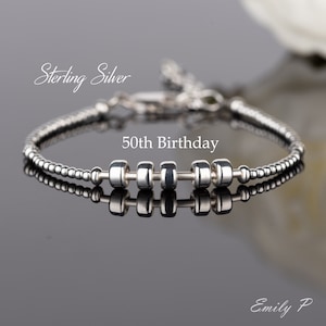 May include: Sterling silver bracelet with five beads that spell out "50th Birthday".