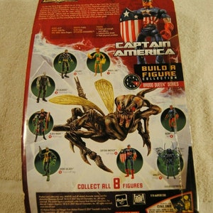May include: Marvel Legends action figure packaging featuring Captain America and a Brood Queen. The packaging includes images of other figures in the series, with the text "Build a Figure Collection" and "Collect All 8 Figures."