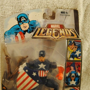 May include: Marvel Legends Captain America action figure in original packaging. The figure is wearing a blue and white costume with a star on the chest and holding a shield with red and white stripes. The packaging includes comic book style art.