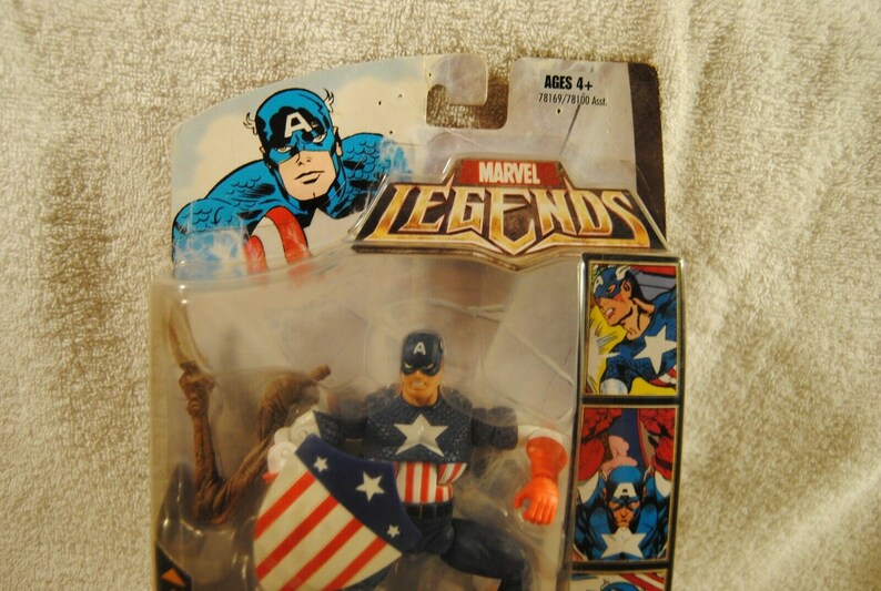 May include: Marvel Legends Captain America action figure in original packaging. The figure is wearing a blue and white costume with a star on the chest and holding a shield with red and white stripes. The packaging includes comic book style art.