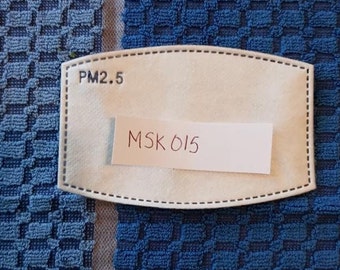 May include: White filter for a face mask with the text "PM2.5" and "MSK 015" written on it.