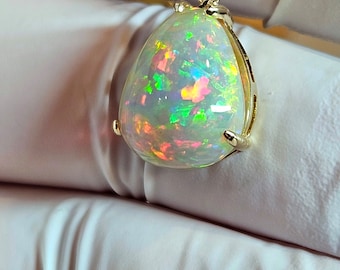 May include: A teardrop-shaped opal pendant with a gold setting. The opal is iridescent with flashes of green, pink, and blue.