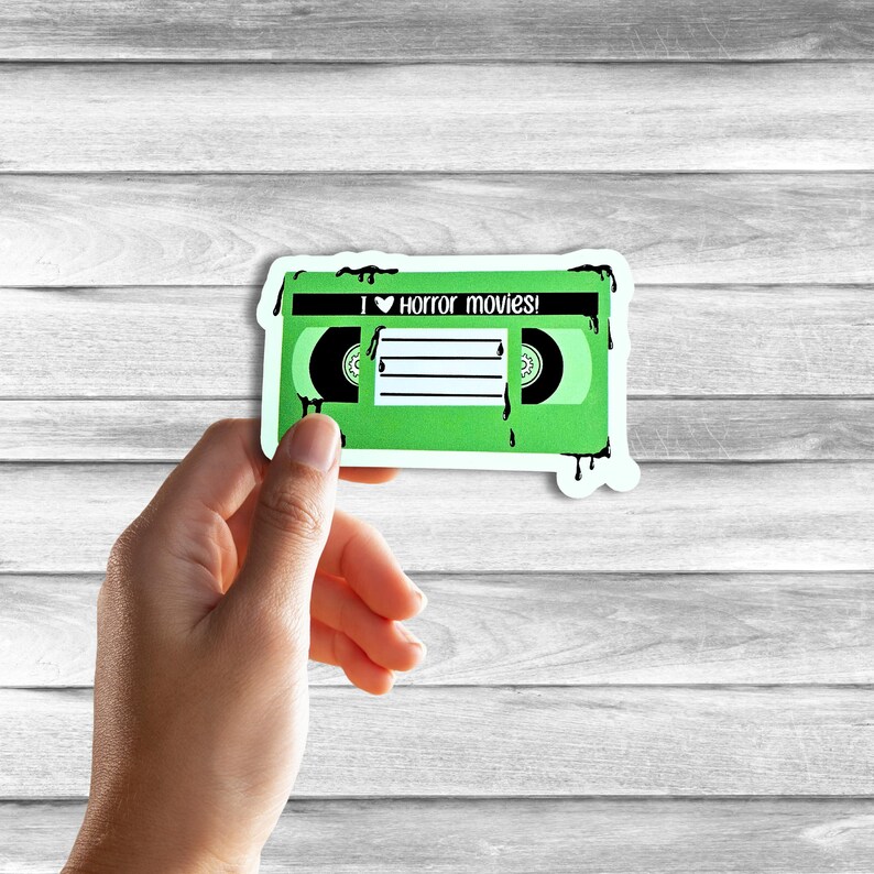 May include: Green VHS tape sticker with dripping black paint. The sticker says "I &hearts; Horror movies!"