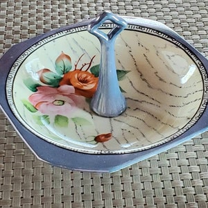 May include: A blue and white ceramic serving dish with a handle. The dish is decorated with a floral pattern and a light brown marbled design.