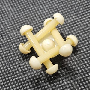 May include: A white plastic puzzle with six pieces that interlock to form a cube shape. The puzzle is made of six pieces that are connected by a central ball.