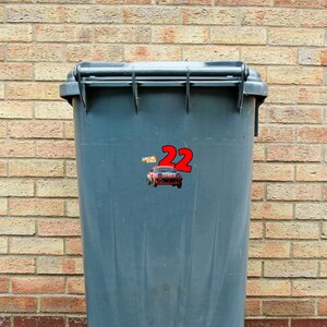 May include: A gray plastic trash can with a red and white sticker that says "Special Stage 22" and a red cartoon car on it.
