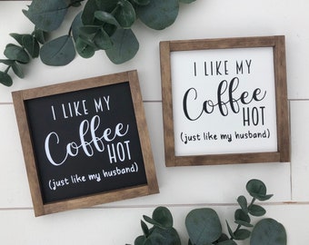May include: Two wooden signs with the text "I like my coffee hot (just like my husband)" on them. The signs are in a rustic style and have a black and white color scheme.