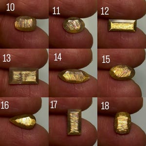 May include: A collection of nine faceted sunstone gemstones labelled 10 through 18, each displaying a metallic golden shimmer known as aventurescence. The stones are presented in various shapes including oval, rectangular, marquise, pear, and cushion cuts.