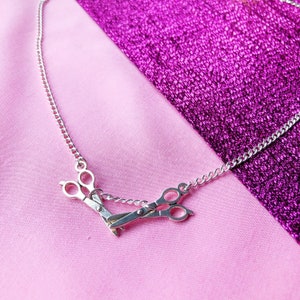 Silver necklace with two scissor charms facing each other, lesbian pride symbol