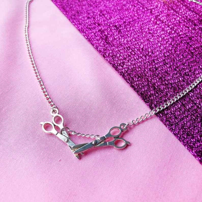 Silver necklace with two scissor charms facing each other, lesbian pride symbol