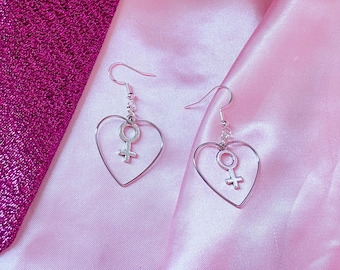 Venus-bedel en liefdeshartoorbellen, oorbellen met vrouwelijk symbool. Zilverkleurige Venus-bedeloorbellen, feministisch, lesbienne, sapphic, WLW