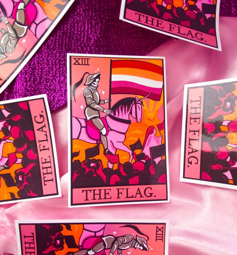 May include: A tarot card with a pink unicorn and a knight riding it. The card is set against a crowd of people and a sunset. The card is labeled "The Flag" and has the number "XIII" in the top left corner. The flag in the background is orange, white, and pink.