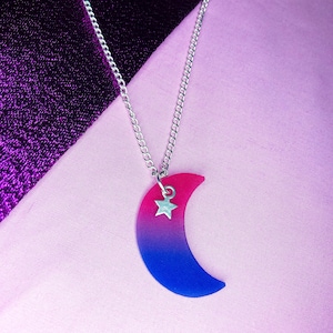 May include: A silver chain necklace with a crescent moon pendant. The moon is made of pink and blue resin and has a small silver star charm.