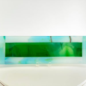 May include: A rectangular glass serving tray with a white background and a green center panel. The tray has a light blue border and a subtle swirl pattern.