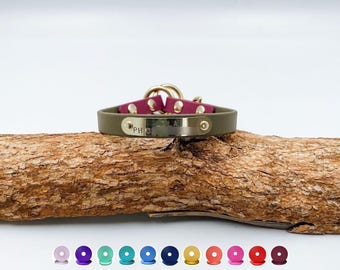 May include: An olive green collar featuring a gold-toned metal nameplate engraved with the name Lola and a phone number. The collar includes magenta accents, gold-toned hardware, and a circular ring. Below are ten small circular color swatches.