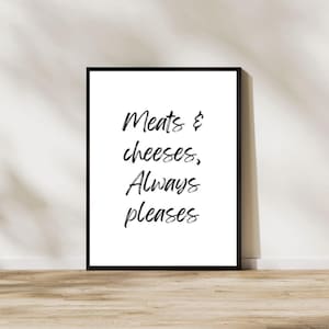 May include: Black and white typography print with the text "Meats & cheeses, Always pleases" on a white background in a black frame.