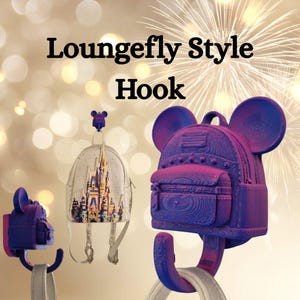 May include: Purple and pink Loungefly Style Hook shaped like a backpack with mouse ears. The hook is holding a clear backpack with a castle design. The text "Loungefly Style Hook" is at the top of the image.