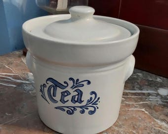 May include: White ceramic tea canister with a blue and white floral design and the word "Tea" in a decorative font.
