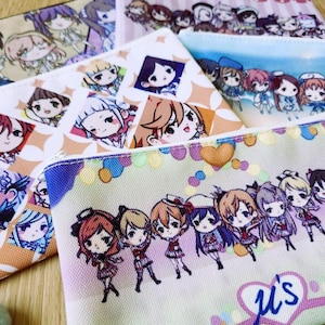 May include: Several zippered pouches with anime-style character illustrations. The pouches showcase diverse designs with various characters, patterns, and colour schemes, ideal for carrying small items.
